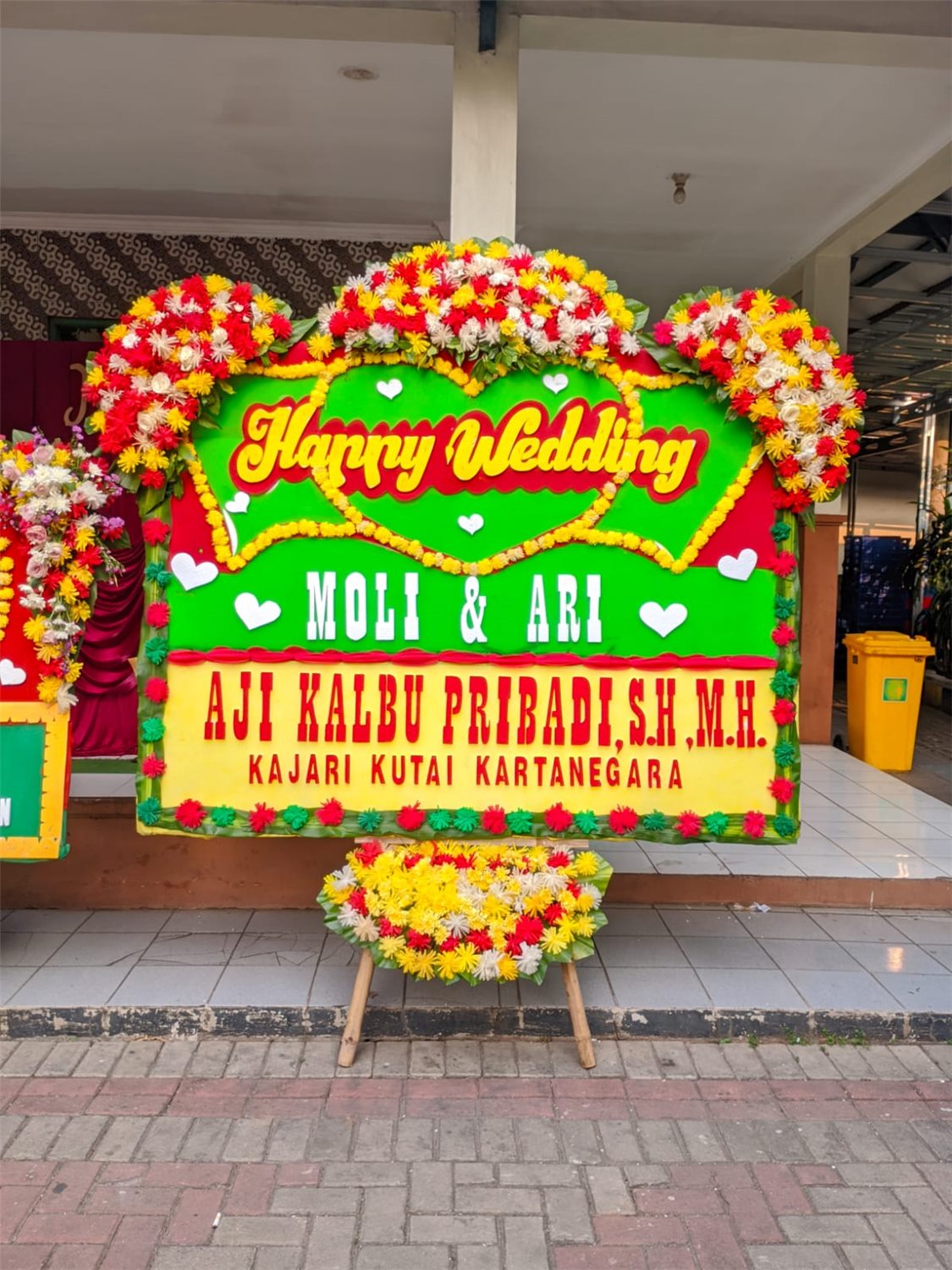 Papan bunga happy wedding dengan rangkaian bunga segar
